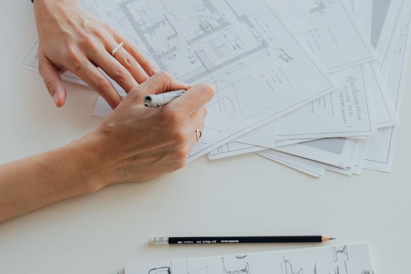 An architect’s hands reviewing and drawing a plan, illustrating deliberate design before delivery.