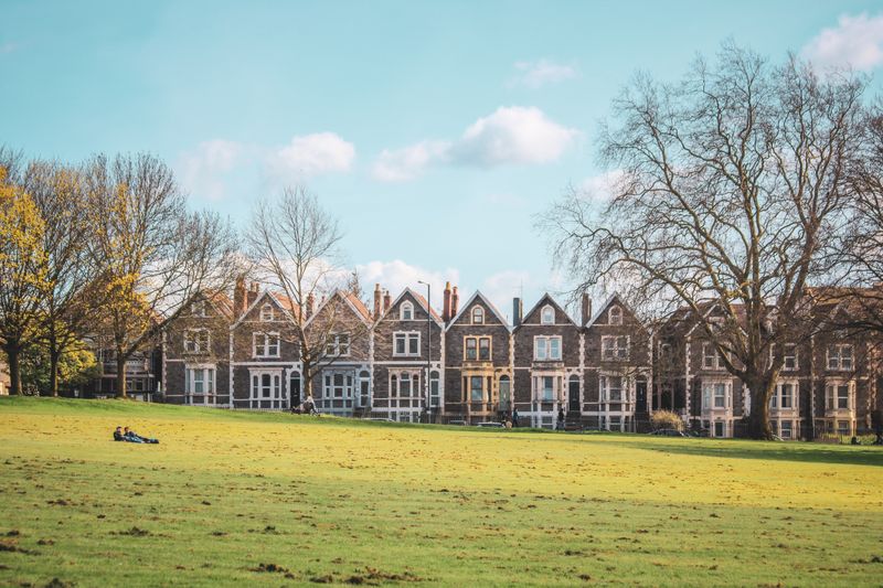 A terrace of Victorian homes beside a park.