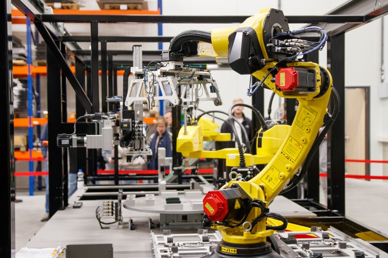 A yellow robot arm working on a production line.